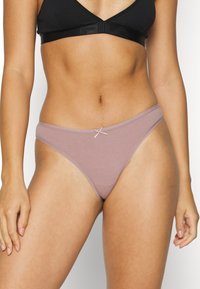 Helle Mauve-Thongs aus weichem Stoff, mit einer glatten Oberfläche und einem kleinen passenden Schleifenakzent am Bund.