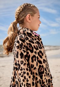 Leopard-patterned fleece hoodie in beige and black, featuring a high collar and a pocket, with a soft, textured finish.