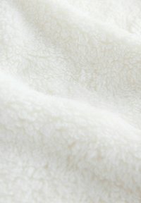 Hvidt plysstof med en blød, fluffy tekstur og en let glans, der har et løkke mønster på overfladen. Velegnet til hyggelige applikationer.