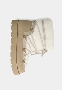 Bota de invierno beige con un upper texturizado y un forro de piel sintética blanca. Presenta cordones y una suela gruesa con relieve para mayor tracción.