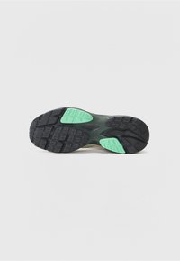 Black rubber outsole with green accents, featuring a textured pattern for traction and durability, designed for athletic footwear.