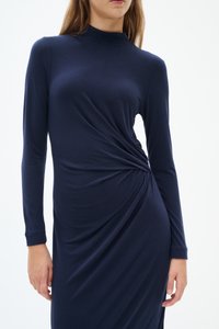 Marinblå långärmad klänning i mjukt material, med en så kallad mock neck och rynkade detaljer på sidan, vilket skapar en draperad look.