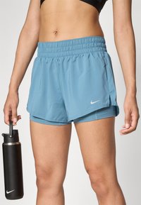 Pantalones cortos deportivos de color azul claro con cinturilla elástica y forro interior, que presentan un logo de Nike en el costado y un diseño en capas.