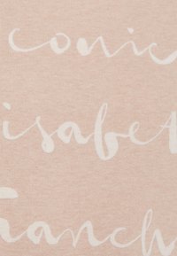 Tejido de color rosa claro con texto blanco escrito a mano. La textura es suave y lisa, sin patrones ni acentos visibles.