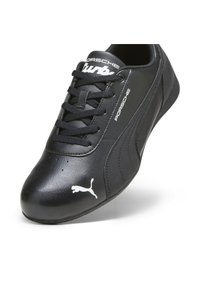 Baskets en cuir noir avec perforations, bout arrondi, lacets et logo Puma blanc sur le côté. Marque Porsche Design sur la languette.