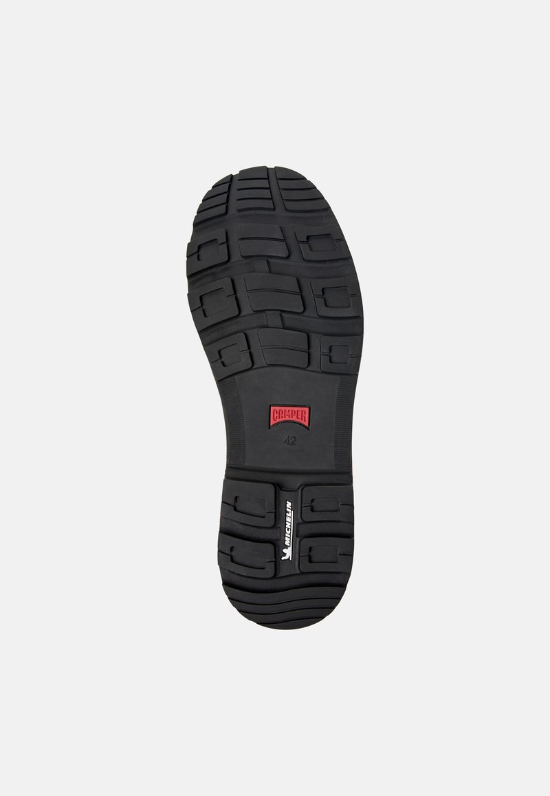 Czarna gumowa podeszwa buta z teksturowanym wzorem grip. Zawiera logo "CAMPER" oraz rozmiar "42", a także szczegół z logiem "MICHELIN".