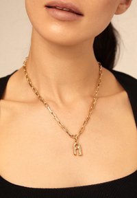 Collar de cadena de oro con eslabones alargados y un colgante con la letra "A", con un acabado pulido y una textura suave.