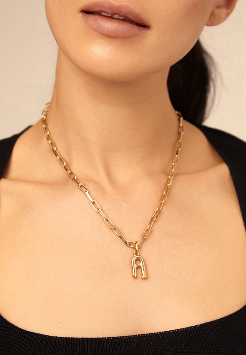Collar de cadena de oro con eslabones alargados y un colgante con la letra "A", con un acabado pulido y una textura suave.