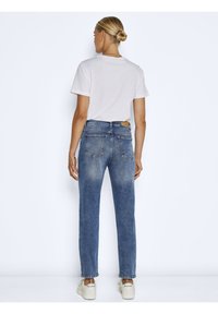 Blaue Denim-Jeans mit verwaschener Textur, hoher Taille, geradem Schnitt und Gesäßtaschen. Kombiniert mit einem schlichten weißen T-Shirt und Sneakers.