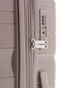 Maleta rígida gris con superficie texturizada, tiradores de doble cremallera, un candado de combinación y un asa lateral para un fácil transporte.