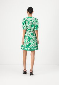 Groene bloemenjurk met pofmouwen, een getailleerde taille en een gekruide zoom. De stof is lichtgewicht met een levendig bloemenpatroon en een subtiele glans.