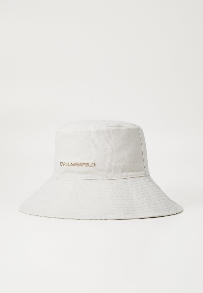 Ljusgrå skärmhatt i slät tyg. Har en vid brätte och ett präglat "KARL LAGERFELD"-logotyp i roséguld framtill.