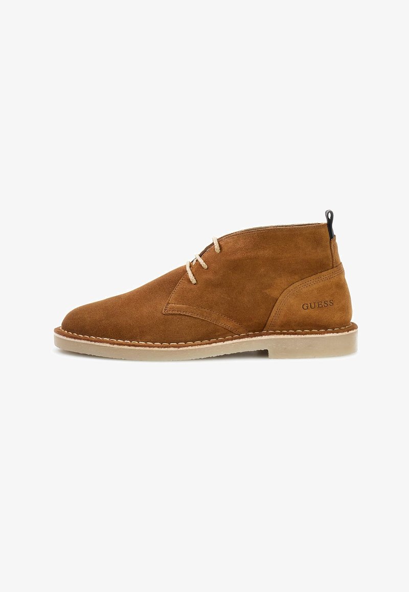 Bottine marron en daim à lacets avec semelle beige et logo « GUESS » embossé près du talon, vue de profil sur fond blanc.