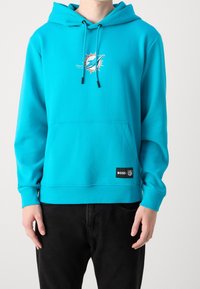 Turkos hoodie med känguruficka, dragsko i huvan och logodetalj. Tillverkad av slät tyg. Har en svart etikett med vit text.