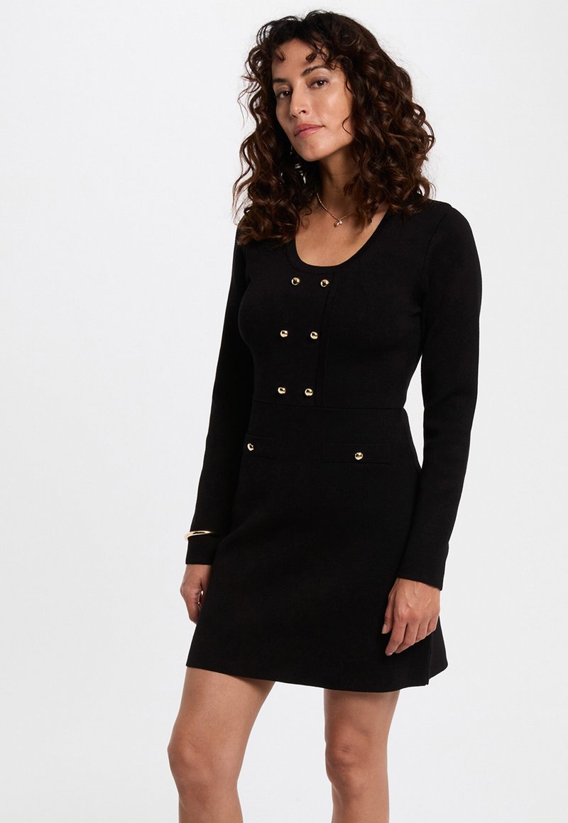 Sort langærmet kjole med tætsiddende krop, guldbesatte knapper og to forlommer. Glat tekstur, knælang med let vidde.