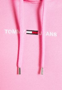 Vaaleanpunainen hupullinen paita pehmeästä kankaasta, jossa neulottu tekstuuri. Siinä on valkoinen "TOMMY"- ja "JEANS"-kirjailu sekä monivärinen logokoriste.