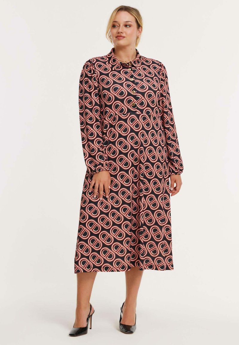 Zwart lange mouw jurk met een gedurfde roze en witte geometrische print. Kenmerken van een kraag en knopen aan de voorkant. Glad stofgevoel.