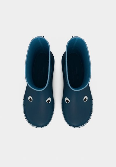 Μπλε λαστιχένιες μπότες με ομαλή υφή, που διαθέτουν υπερμεγέθη λευκά διακοσμητικά στο πάνω μέρος, στρογγυλεμένη μύτη και υφή στην σόλα.