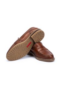 Brown leather loafers with a smooth finish, featuring stitching details and a patterned outsole. Flexible rubber sole with a slight heel.