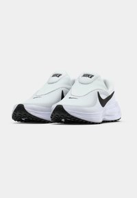 Chaussures de sport blanches avec tige en mesh respirant, logo Nike noir et semelle extérieure en caoutchouc noir texturé. Design élégant et arrondi.