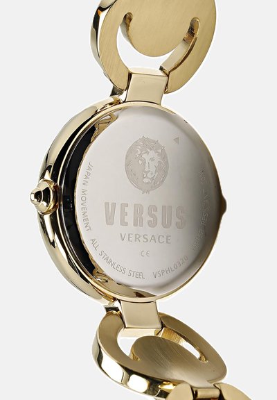 Zlaté nerezové hodinky s okrúhlym puzdrom. Na zadnej strane je vygravírované logo Versus Versace a dizajn leva. Zaoblené, hladké hrany.