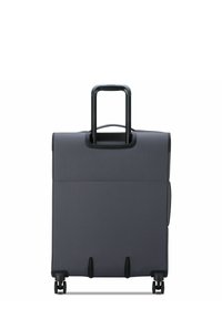 Maleta blanda gris con un mango negro retráctil, cuatro ruedas y una textura suave. Presenta un diseño limpio y minimalista.