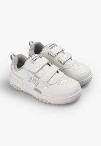 Zapatillas blancas con acentos grises, parte superior de cuero texturizado, dos correas de Velcro, área de los dedos perforada y un logo de calavera y huesos cruzados.