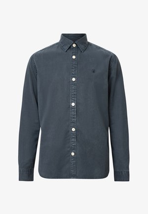 Knapplistad skjorta i mörk marinblå bomull med spetsig krage, långa ärmar och vita knappar. Har en liten broderad logga på bröstet.