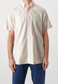 Lichtroze overhemd met korte mouwen en knopen, met een kraag, voorzien van een klein geborduurd logo en een subtiele textuur.