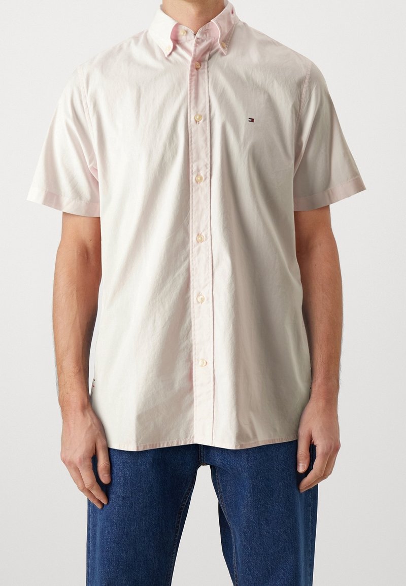 Lichtroze overhemd met korte mouwen en knopen, met een kraag, voorzien van een klein geborduurd logo en een subtiele textuur.