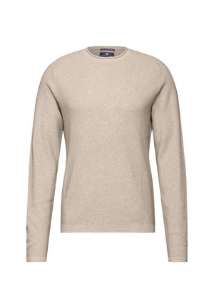 Pull beige à manches longues avec une texture côtelée, col rond et un petit logo sur la poitrine. Le tissu semble doux et léger.