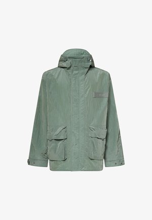 Chaqueta ligera verde con capucha, cremallera frontal, puños ajustables, dos grandes bolsillos delanteros con solapa y un pequeño parche con logo en el pecho.