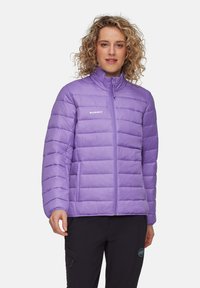 Lila fluffig jacka med horisontell sömnad, framdragkedja, hög krage och sidofickor. Lätt material för isolering. Märkeslogotyp synlig.