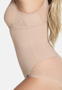Beige shapewear van een soepel, rekbaar materiaal met een ribbelstructuur in het bovenste gedeelte. Het ontwerp heeft naadloze randen en een lengte tot halverwege de dij.