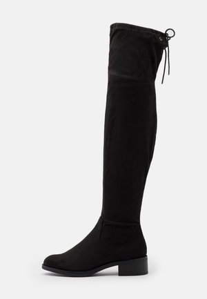 Botte noire au-dessus du genou en suède doux, avec un bout arrondi, un talon largeur et un cordon de serrage ajustable en haut pour un ajustement parfait.