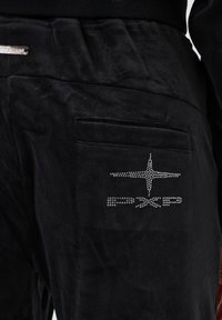 Zwarte velours broek met een achterzak, voorzien van een strassontwerp van sterren en het "PXP"-logo, soepel van textuur en met een elastische tailleband.