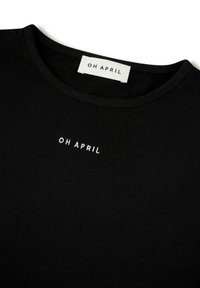 Svart t-skjorte laget av bomull, med rund hals og liten hvit "OH APRIL" logo på forsiden. Glatt tekstur, enkelt design.
