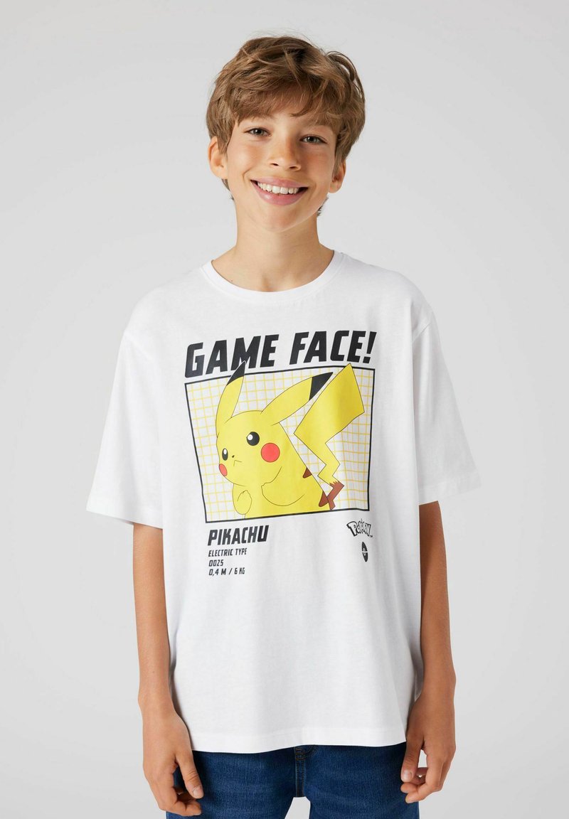 Bela majica s kratkimi rokavi, ki prikazuje grafiko Pikachuja v rumenem okvirju z napisom "IGRALNO OBRAZ!" in podrobnostmi o Pikachuju. Izdelek je iz bombaža in ima ohlapen kroj.