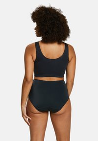 Soutien-gorge noir sans couture avec bretelles larges, associé à un slip taille haute assorti, présentant un tissu lisse et un design minimaliste.