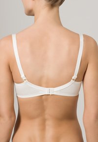 Bra bianco in cotone con spalline regolabili e chiusura a gancio. Texture liscia, design minimalista e dettagli di cucitura discreti.