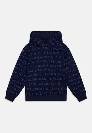 Felpa navy con motivo di testo ripetuto in azzurro chiaro "CALVIN KLEIN JEANS". Presenta un cappuccio con cordino e polsini e fondo a costine. Texture del tessuto soffice.
