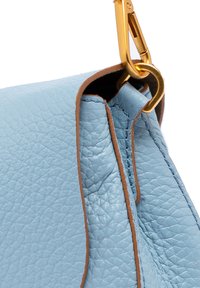 Borsa di pelle azzurro chiaro con superficie texturizzata, cuciture marroni e accessori dorati con gancio. Vista dettagliata del bordo superiore e del punto di attacco per la tracolla.