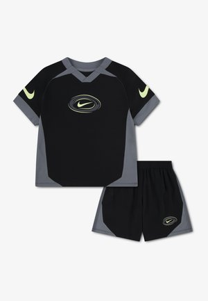Ensemble de sport Nike noir et gris avec manches courtes et shorts, comportant des logos Nike swoosh jaunes sur la poitrine, les manches et les shorts.