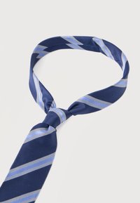 Γραβάτα σε ναυτικό μπλε με ανοιχτό μπλε και λευκές διαγώνιες ρίγες, χαλαρά δεμένη σε απλό λευκό φόντο.