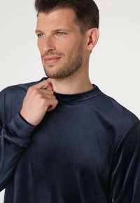 Maglietta a maniche lunghe blu navy realizzata in tessuto morbido. Presenta un collo alto e maniche aderenti, offrendo un aspetto liscio e elegante.