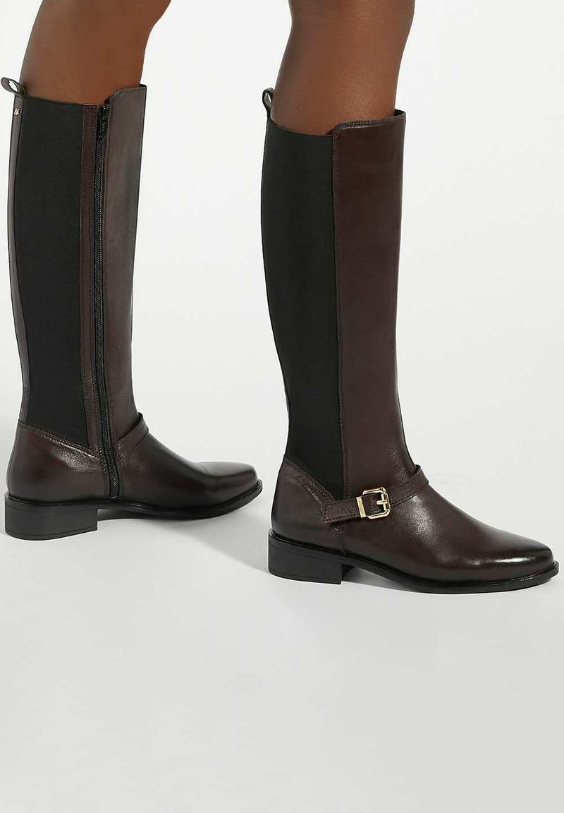 Brown leather high-heel boots with elastic side panels, zipper closure, and buckle accent. Smooth texture and rounded toe design.