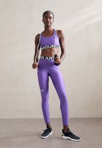 Top corto atlético morado y leggings con marcas negras. Incluye una cuerda para saltar y zapatillas deportivas negras con suelas texturizadas. Textura suave.