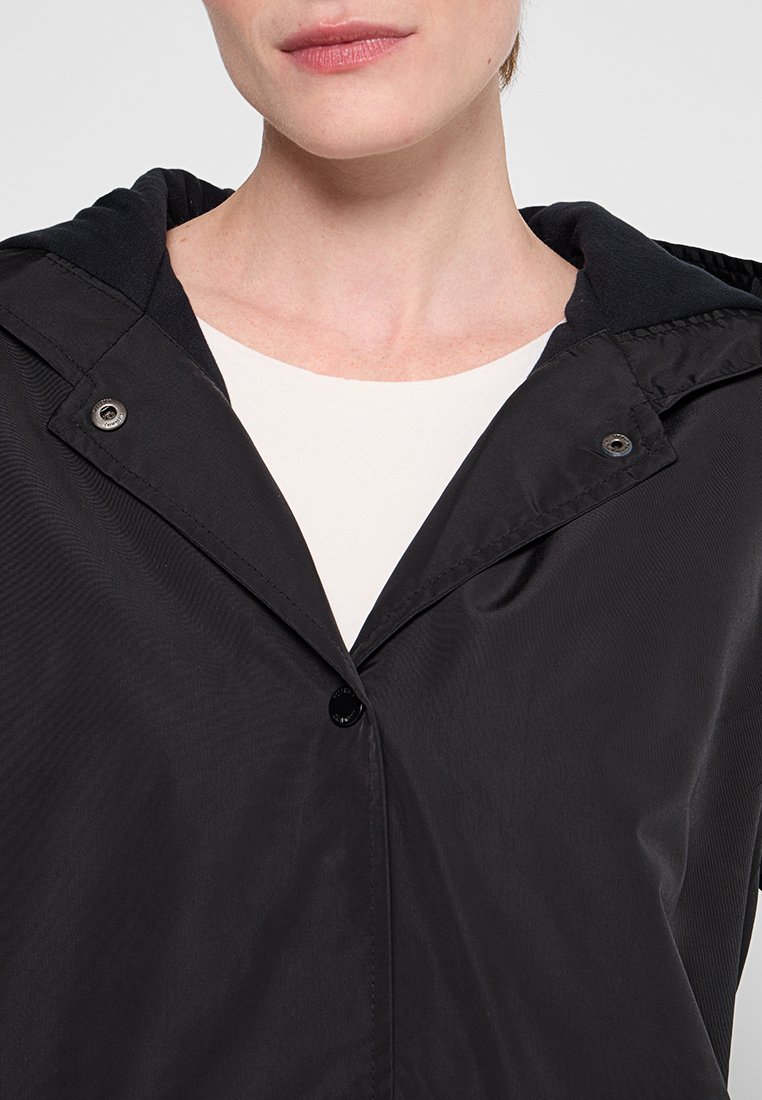 Schwarze Jacke mit Kapuze, mit einem Knopfverschluss, glatter Textur und kontrastierender Innenauskleidung. Einfaches Design ohne Muster.