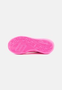 Heldere roze sneakerzool met intricate geometrische en doolhofachtige looppatronen, inclusief logo's en textuurlijke gripzones op een witte achtergrond.
