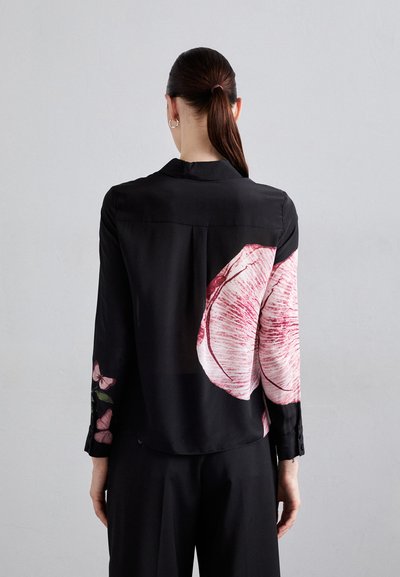 Blusa di seta nera con grandi stampe floreali in tonalità di rosa, maniche lunghe con polsini abbottonati e una texture liscia e lucida.